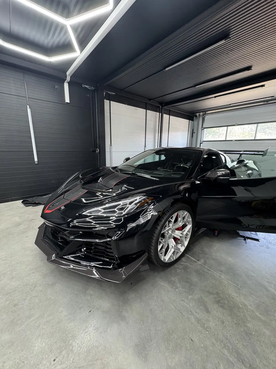 Чёрный Chevrolet Corvette ZR1 в зале Redlines под шестиугольным освещением