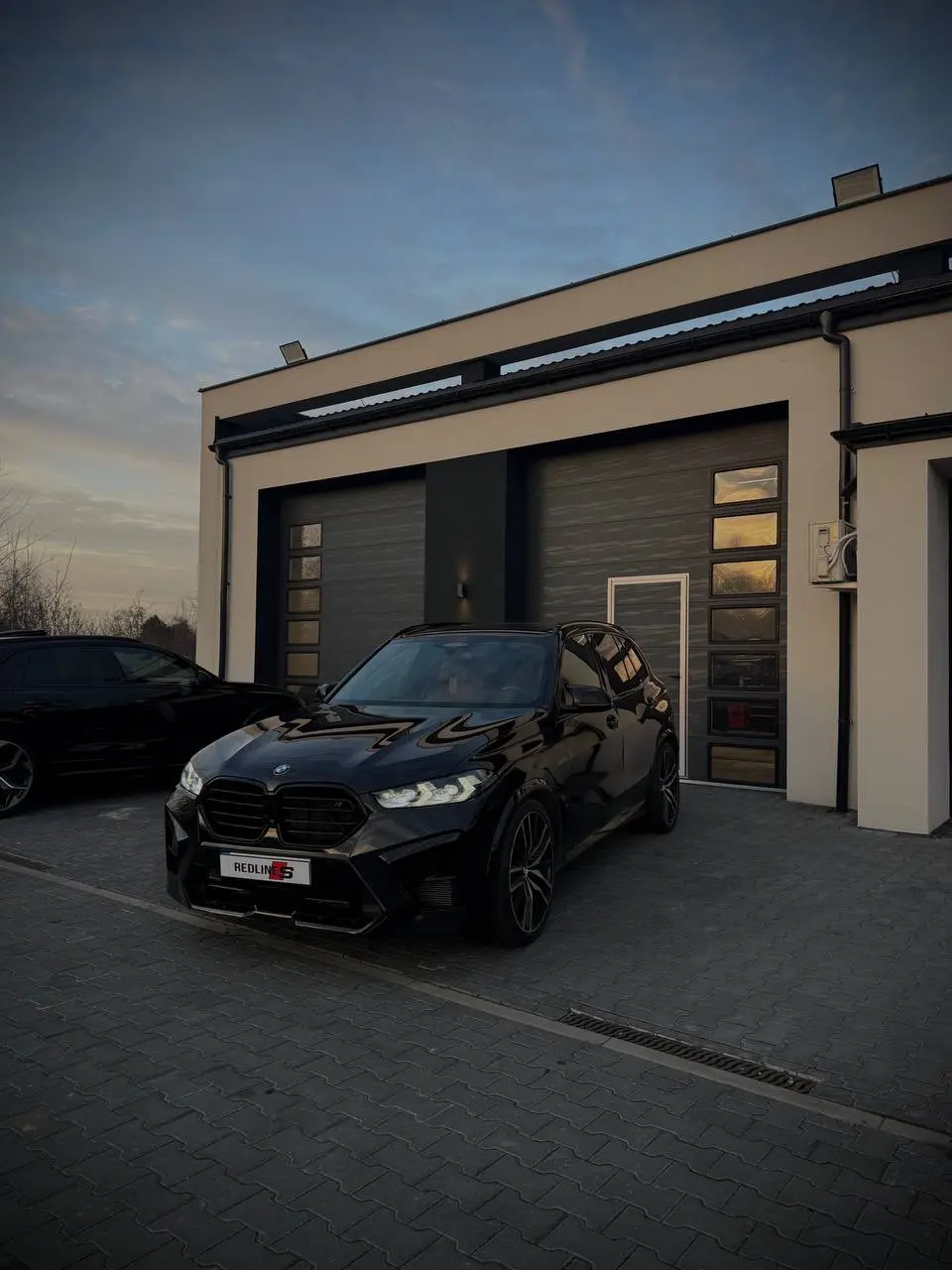 Redlines Car Service at dusk with a BMW X5 M in front