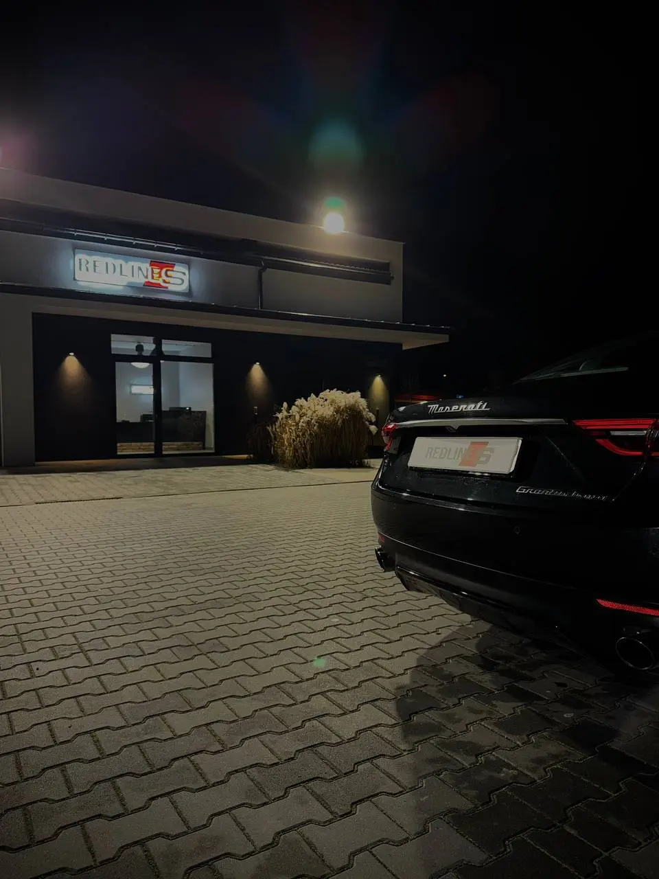 Maserati GranTurismo at night in front of the illuminated Redlines sign